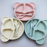 Two bear-shaped plates with cutlery on a wooden surface