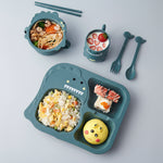 Children's lunch set with dinosaur-shaped tray, bowls, and cutlery on a blue background