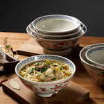 Bowl of noodles with a decorative rim on a wooden surface