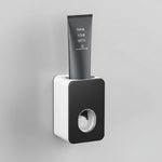 Black and white toothbrush holder with toothpaste on a bathroom wall.
